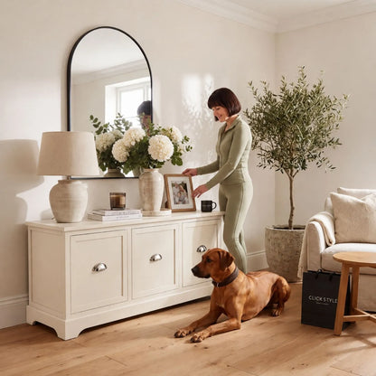 Warm Ivory Pine Wood Low 3 Drawer Storage Unit with Polished Silver Cup Handles styled in a neutral living room with a woman arranging a framed photo and Rhodesian Ridgeback 48x107x39cm | Click Style