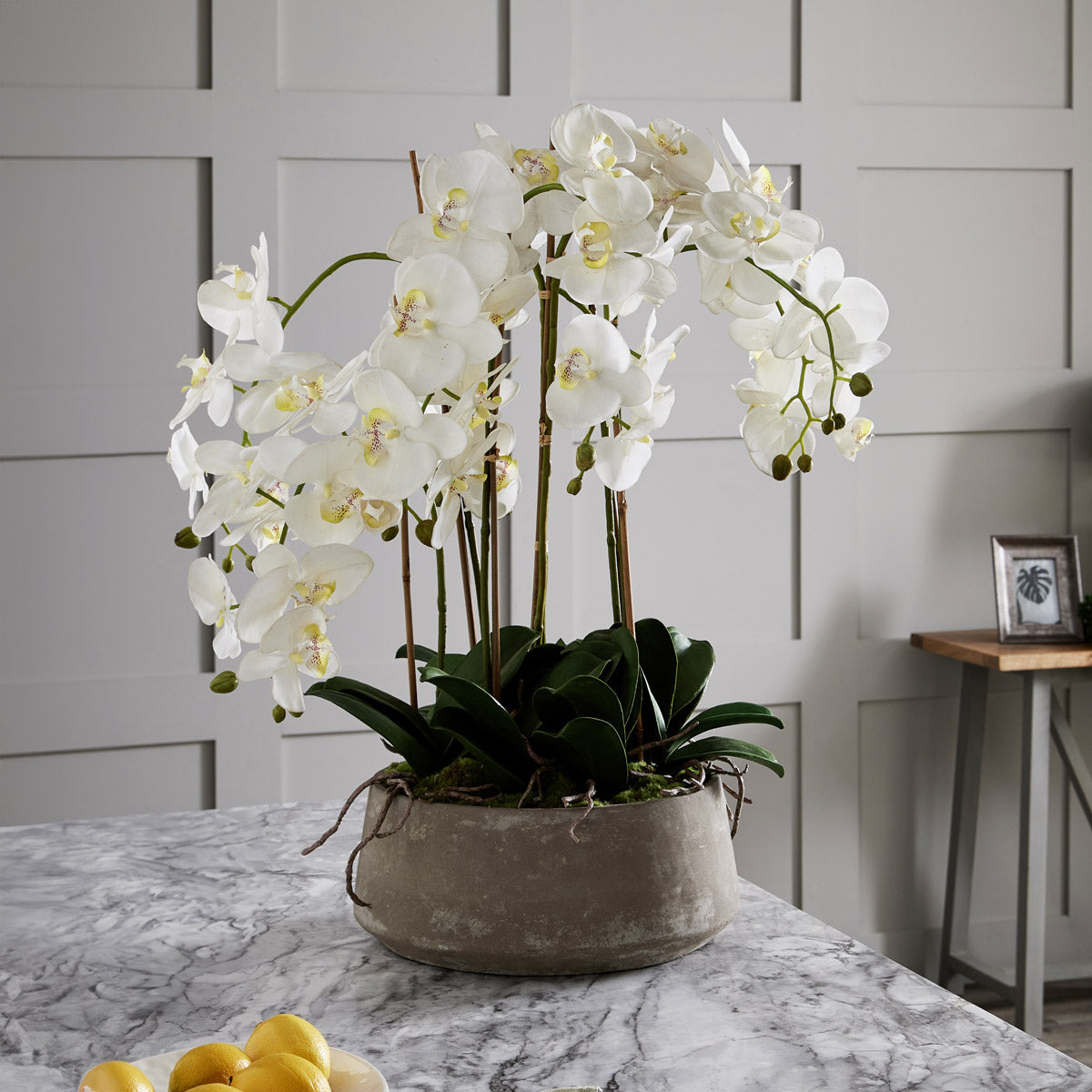 Artificial large white orchid plant in stone pot