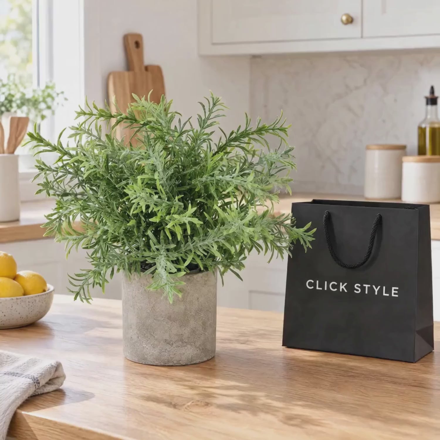 Artificial Rosemary Plant in Grey Stone-Effect Pot with Realistic Green Foliage – Lifelike Faux Potted Herb 24x24x24cm shown in a short lifestyle video on a light oak kitchen worktop with a black shopping bag featuring white CLICK STYLE branding | Click Style