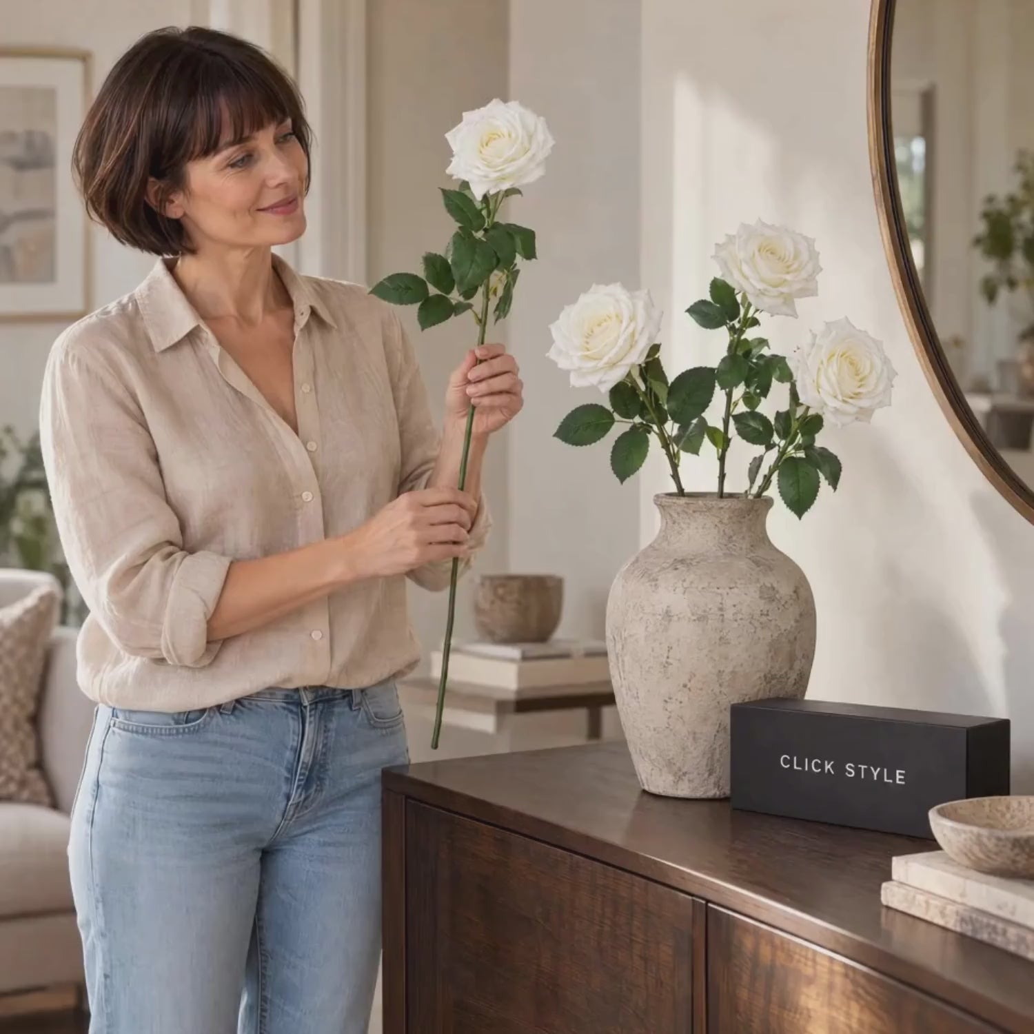 Artificial White Garden Rose with Long Stem & Large Layered Bloom – Lifelike White Faux Rose Flower with Realistic Green Foliage 75cm – Lifestyle video showing a woman gently handling the white rose stem beside a decorative stone vase filled with matching artificial white roses | Click Style