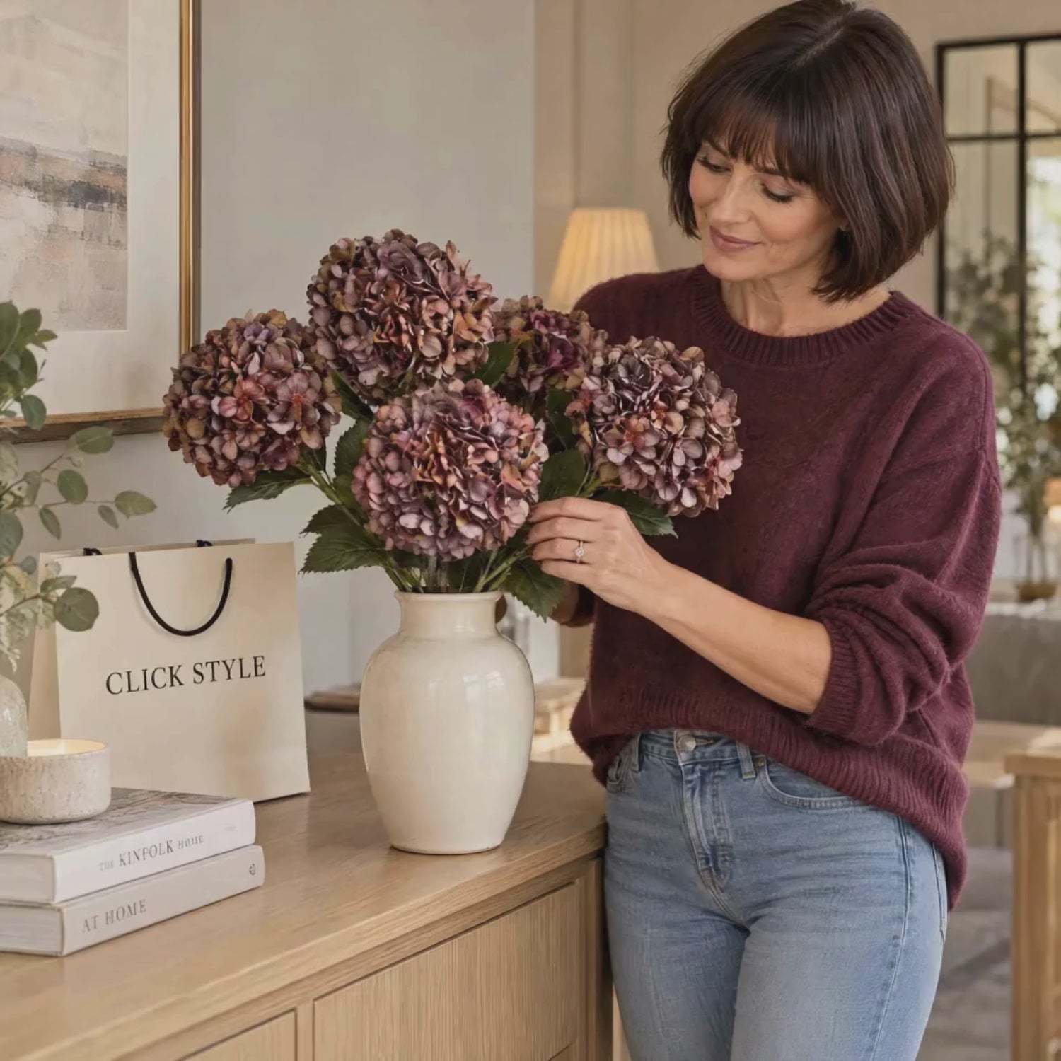 Artificial Antique Mauve & Copper Hydrangea Stem with Burgundy Petals & Realistic Green Leaves – Lifelike Faux Brown Hydrangea Flower 42x18x18cm – Lifestyle Video of Woman Gently Arranging Five Artificial Hydrangea Stems in Cream Ceramic Vase with CLICK STYLE Branding | Click Style